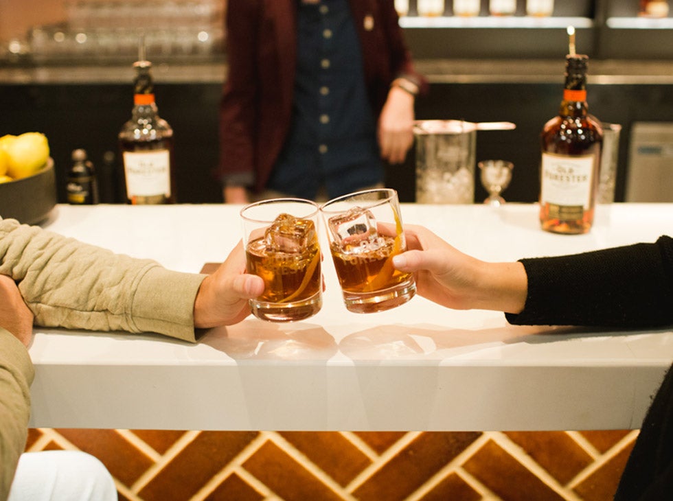 Two people clanking glasses at George's Bar in Old Forester Distillery